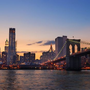 New York City Manhattan skyline and Brooklyn Bridge at dusk over Hudson River with skyscrapers